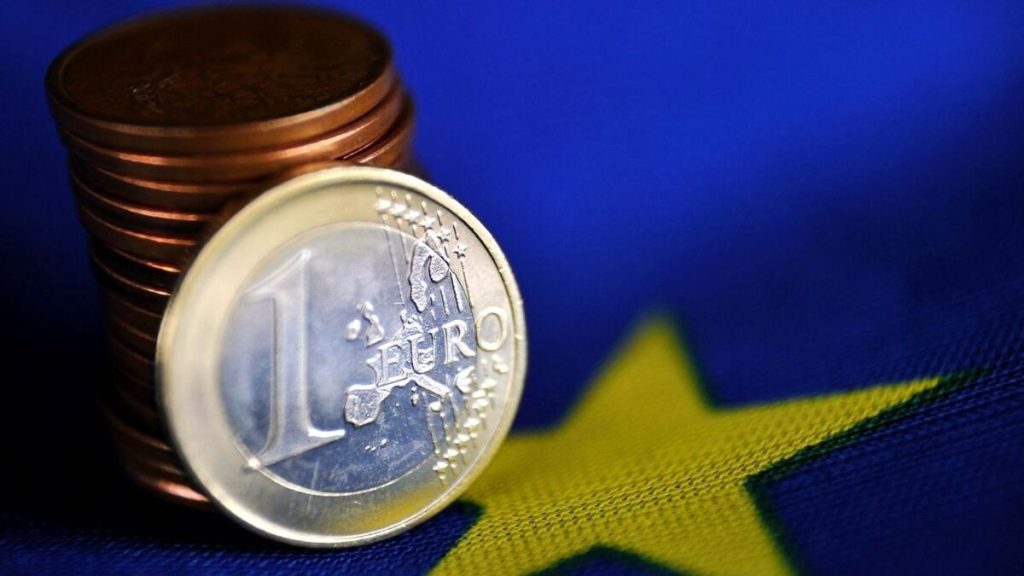 Monedas de euro apiladas sobre el logo de la Unión Europea, representando el crecimiento económico de España.