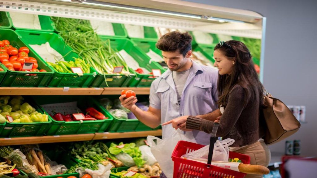 Dos personas en un supermercado de Euskadi llenando un carrito, mientras comparan precios en el contexto de gastos de servicios de Osakidetza.