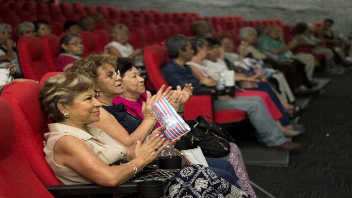 Grupo de adultos mayores disfrutando de una película en el cine.