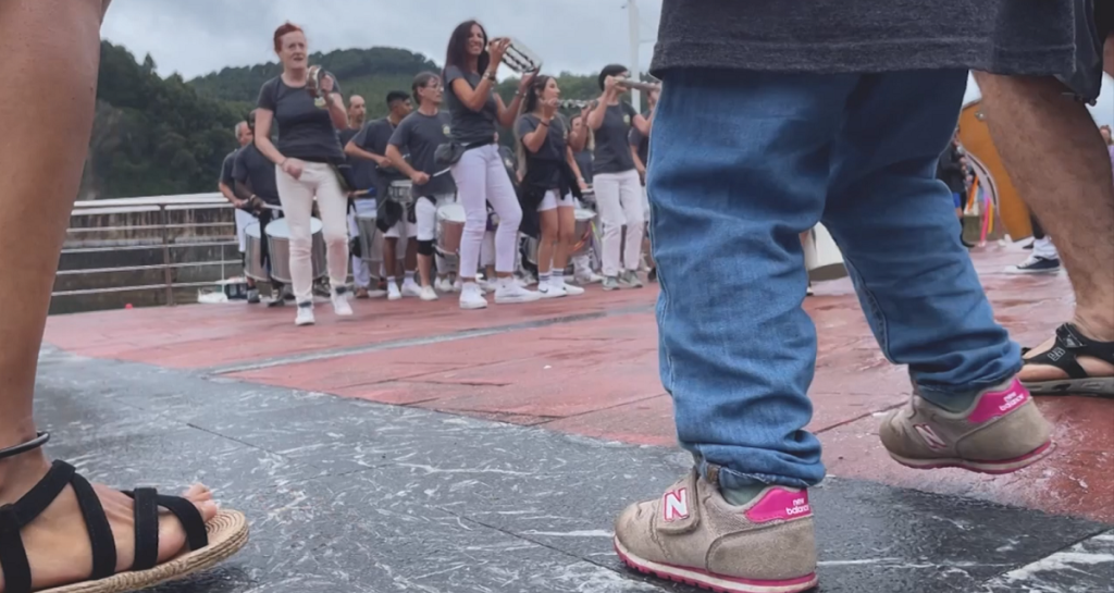 Personas disfrutando del festival de reggae en Armintza, cantando y bailando al ritmo de la música caribeña.
