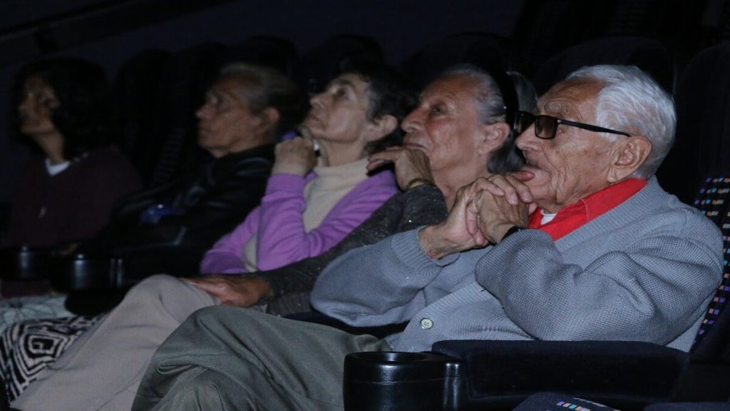 Personas mayores disfrutando de una película en el cine.