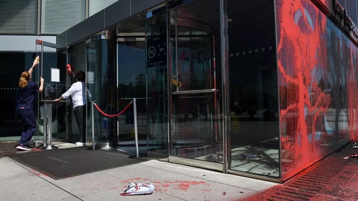 Dos mujeres retiran las marcas hechas con tintas roja y negra por miembros de Futuro Vegetal en el edificio que alberga la embajada británica en España, el 15 de junio de 2023.