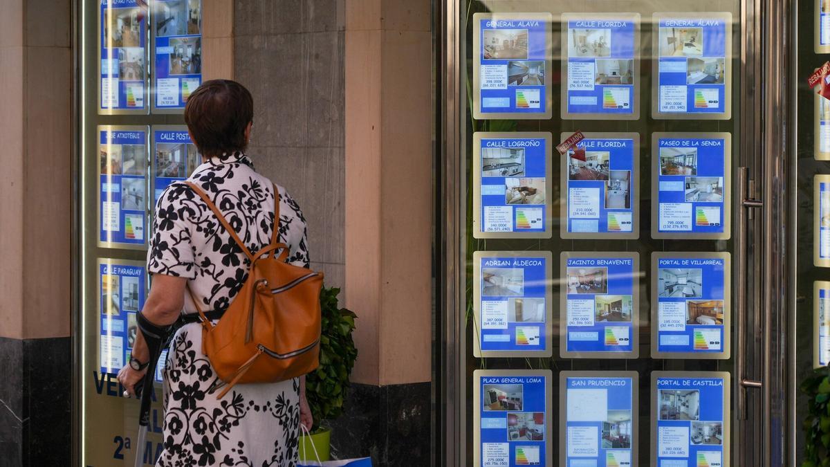 Una persona revisa las ofertas en el escaparate de una agencia inmobiliaria.