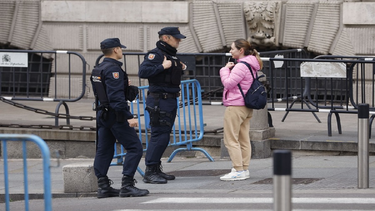 En Madrid, cerca del Congreso de los Diputados, dos policías nacionales charlan con una mujer al lado de unas vallas este martes.